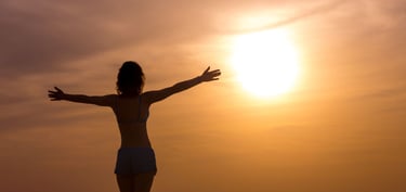 femme libre et heureuse et sereine qui regarde l'horizon en levant les bras