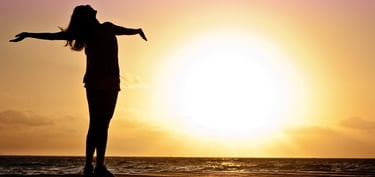 a woman standing on a dock with her arms outstretched out to the water