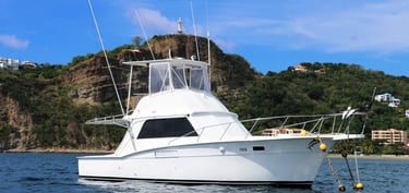 A white Big Fish Tours sportfishing boat anchored in the blue waters of San Juan del Sur, Nicaragua,