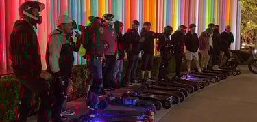 a group of people standing around a group of electric skateboards