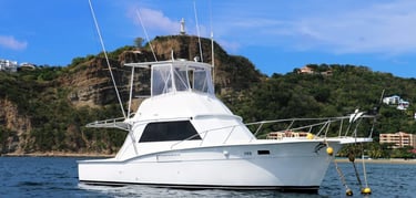 A white Big Fish Tours sportfishing boat anchored in the blue waters of San Juan del Sur, Nicaragua,