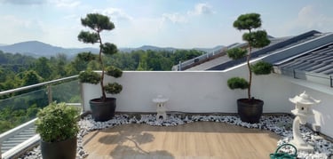 Rooftop Zen garden design in Rawang with decorative bonsai, white pebbles, and stone pagodas.