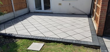 Basic grey patio with black charcoal edging blocks slabs laid in diamond format