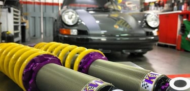 des amortisseurs sport avec une Porsche en arrière plan
