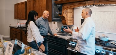 Chef Andrew in luxury kitchen appliance showroom talking with clients.