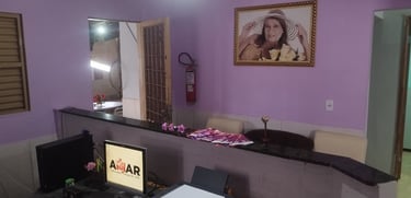 Reception area with purple walls, counter desk, computer monitor, and a framed portrait on the wall.
