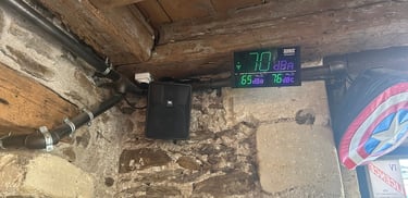 Sonmètre numérique et haut-parleur JBL monté sur un mur en pierre rustique avec des poutres en bois