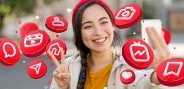 Imagen de una chica joven subiendo una foto a sus redes sociales con emoticones a su alrededor.