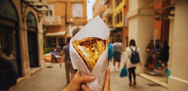 Autora segurando um gyros enquanto caminha pelas ruelas movimentadas de Corfu, explorando a cidade.