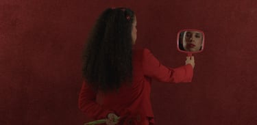 a woman in a red dress is holding a mirror