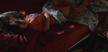 a woman laying on a bed with a blanket