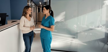 Una paciente y una odontóloga conversando amistosamente en la recepción de una clínica moderna