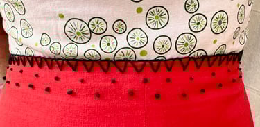 Embroidered waist of a white, green, and red strappy sundress