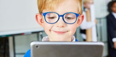 menino crianca de cabelos loiros e oculos azuis vendo celular