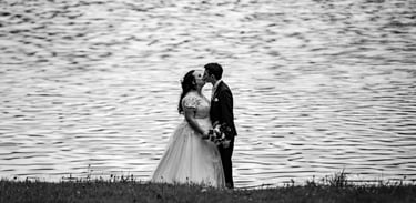 a bride and groom kissing in front of a lake