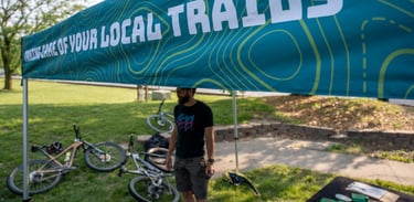Someone standing under the COMOTA tent with bikes laying on the ground
