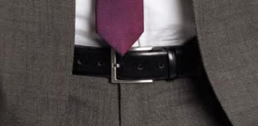 A close up of a monti belt on a man wearing a suit