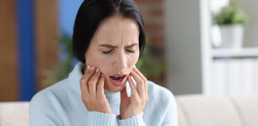 Women touching her jaw in pain, showing symptoms of TMJ disorder.
