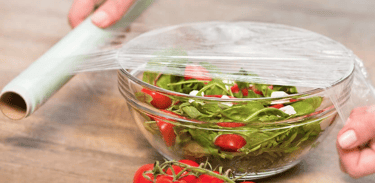 a person is holding a plastic container with tomatoes