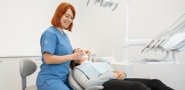 Una dentista sonriente realizando un examen dental a una paciente recostada en el sillón dental