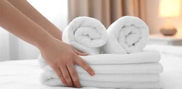 Personne posant des serviettes et du linge de salle de bain sur un lit soigneusement préparé