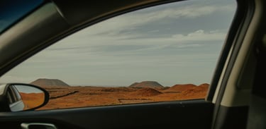 a car window with a view of a desert and volcanoes