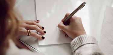 a woman is writing on a piece of paper