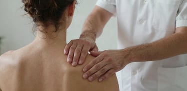 A Southern European therapist performing precise manual therapy on a patient's shoulder, focusing on the calm and professional environment of the clinic.