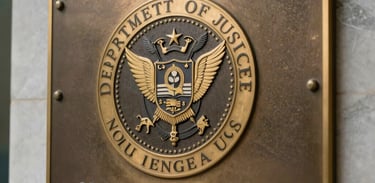 A close-up of a brass plaque featuring the Department of Justice seal mounted on a marble wall, reflecting professional integrity and authority, North American / US.