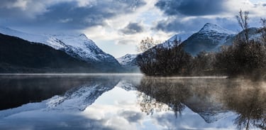 Aerial view of a heart-shaped blue lake surrounded by rocky quarry cliffs and autumn trees.