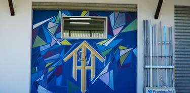 A colorful geometric blue mural painted on an exterior wall at the Franjerplast facility.