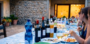 Al fresco Italian dinner featuring penne pasta, wine, and bread served on a patio table at dusk.