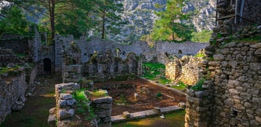 Ruínas de Ólympos em Antália, com vestígios antigos cercados por natureza e céu azul ao fundo