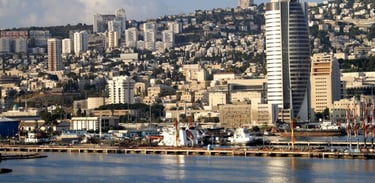 Navio chegando ao Porto de Haifa com vista dos prédios e da cidade ao fundo.