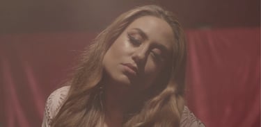 A person with their long brown hair and light brown skin with eyes closed and head tilted right.