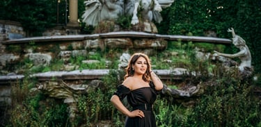 Model posing in elegant black gown near fountain garden, captured by Fred Art Studio.