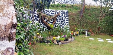 Garden at Nobel Bungalow Nuwara Eliya with Keena plant, flower beds, bench, and decorative pond