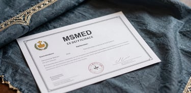 Detailed shot of an official MSME certificate document lying on a desk next to a beautiful hand-embroidered piece of fabric in dark blue-grey.