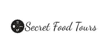 Secret Food Tours official logo featuring cursive typography and a circular food icon on a black background.