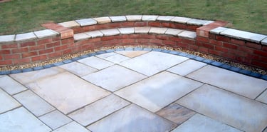 Multi-level sunken sandstone patio step up to lawn with retaining wall