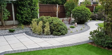 Patio with custom stone circle with aggregates and paving weaving through adventurous garden design