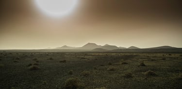 a desert scene with a sun setting in the background