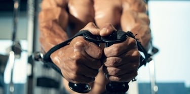 Muscular male bodybuilder performing a cable fly chest workout in a gym for muscle growth.