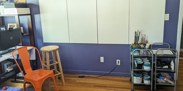 Four stretched canvas panels attached to a wall in an art studio ready for painting to begin.