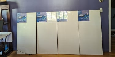 Four 2-foot by 4-foot canvas panels side by side ready to be attached to an empty wall for painting.