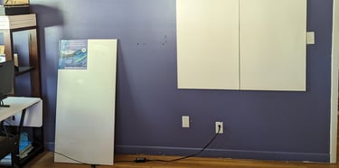 Stretched canvas panels being attached to an art studio wall with Velcro tabs.