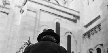homme à chapeau en contre plongée devant le sacré coeur de Paris