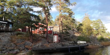 a swedish house is on the waterfront for pike fishing in sweden, there are trees around the house.