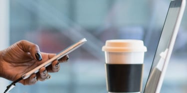 a person sitting at a table with a laptop and a cell phone