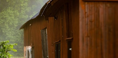 a red barn with a forrest in the backround